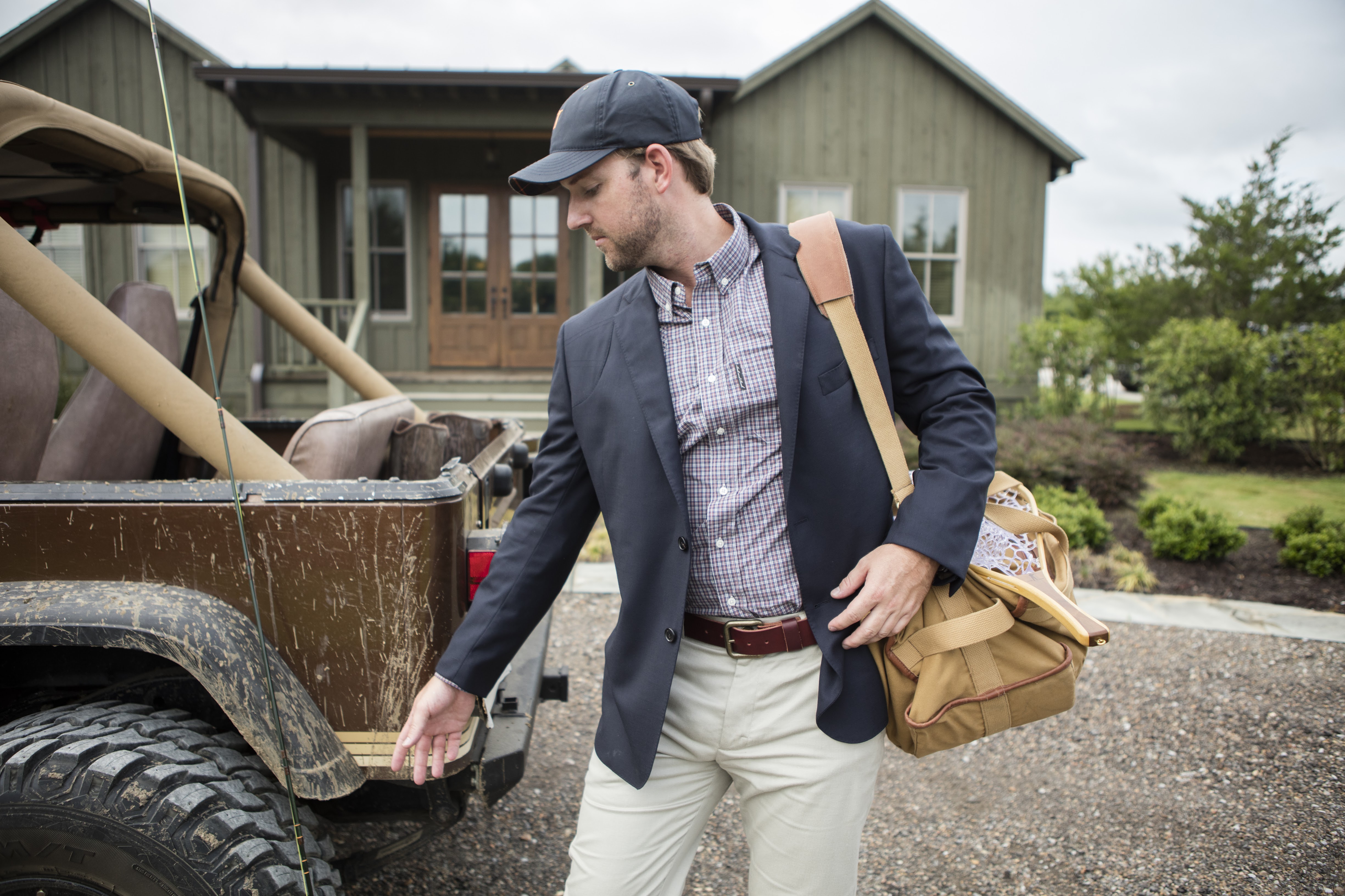 A man carrying a duffle bag over his shoulder as he walks past a Jeep