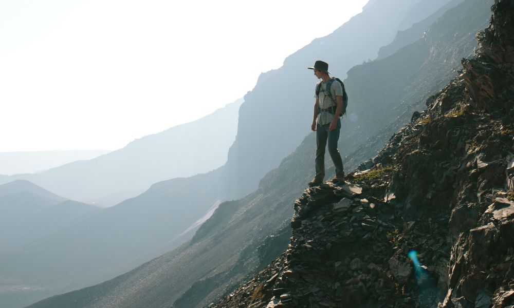 A man with a backpack standing on a rocky ledge.