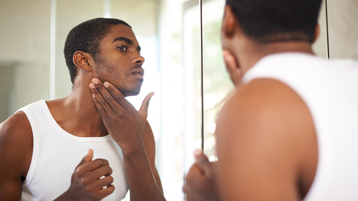 man inspecting his face and jawline in the mirror