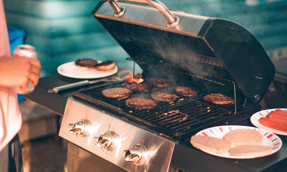 Man using a gas grill in his backyard