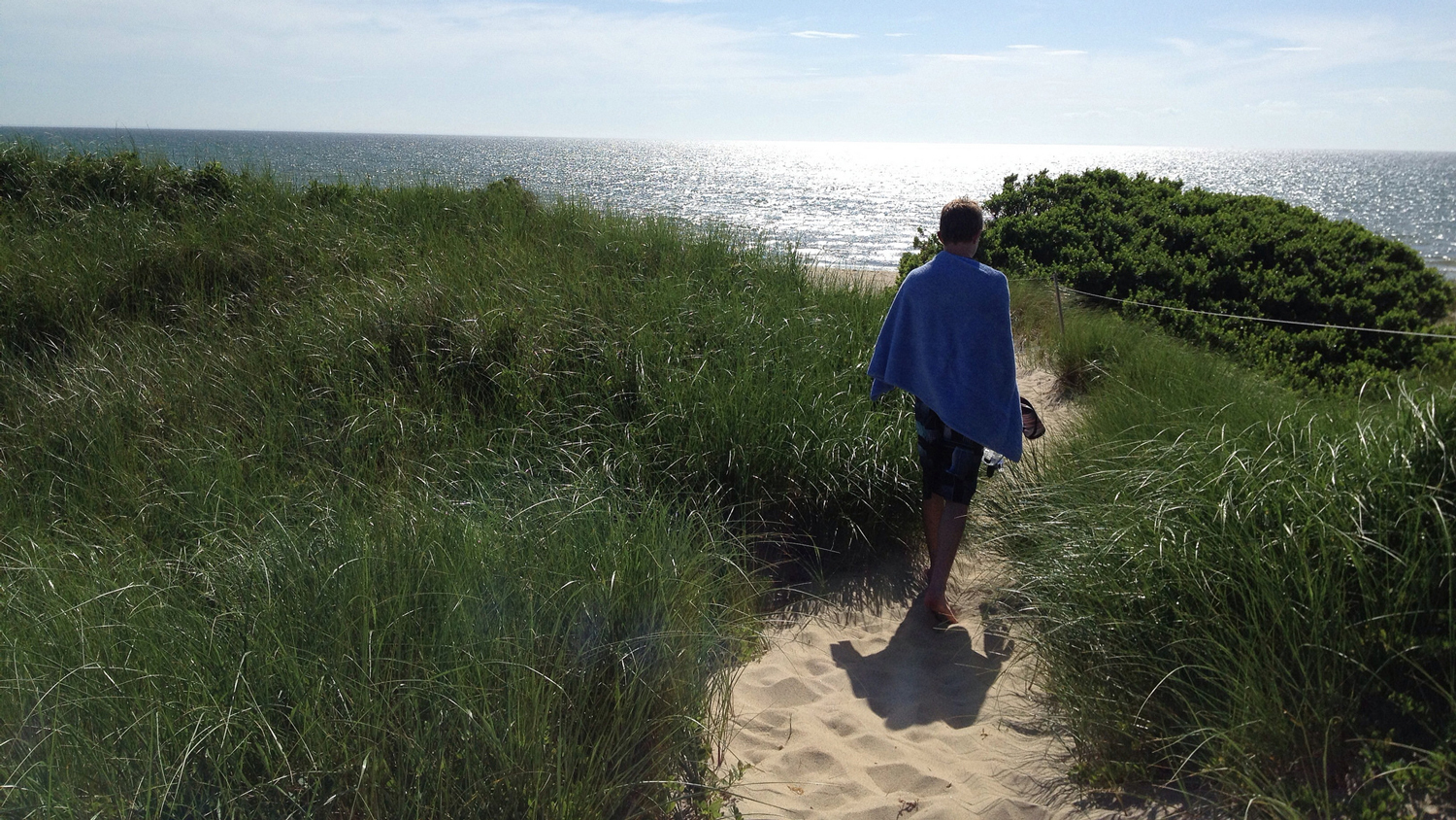 Beachgoer in a towel headed to the beach on Bound Brook Island in Cape Cod, Massachusetts.