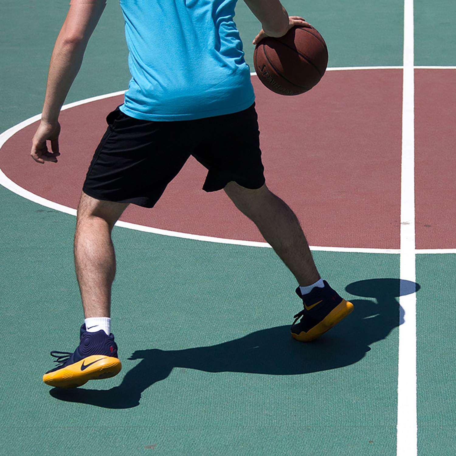 Man playing basketball on an outdoor court square