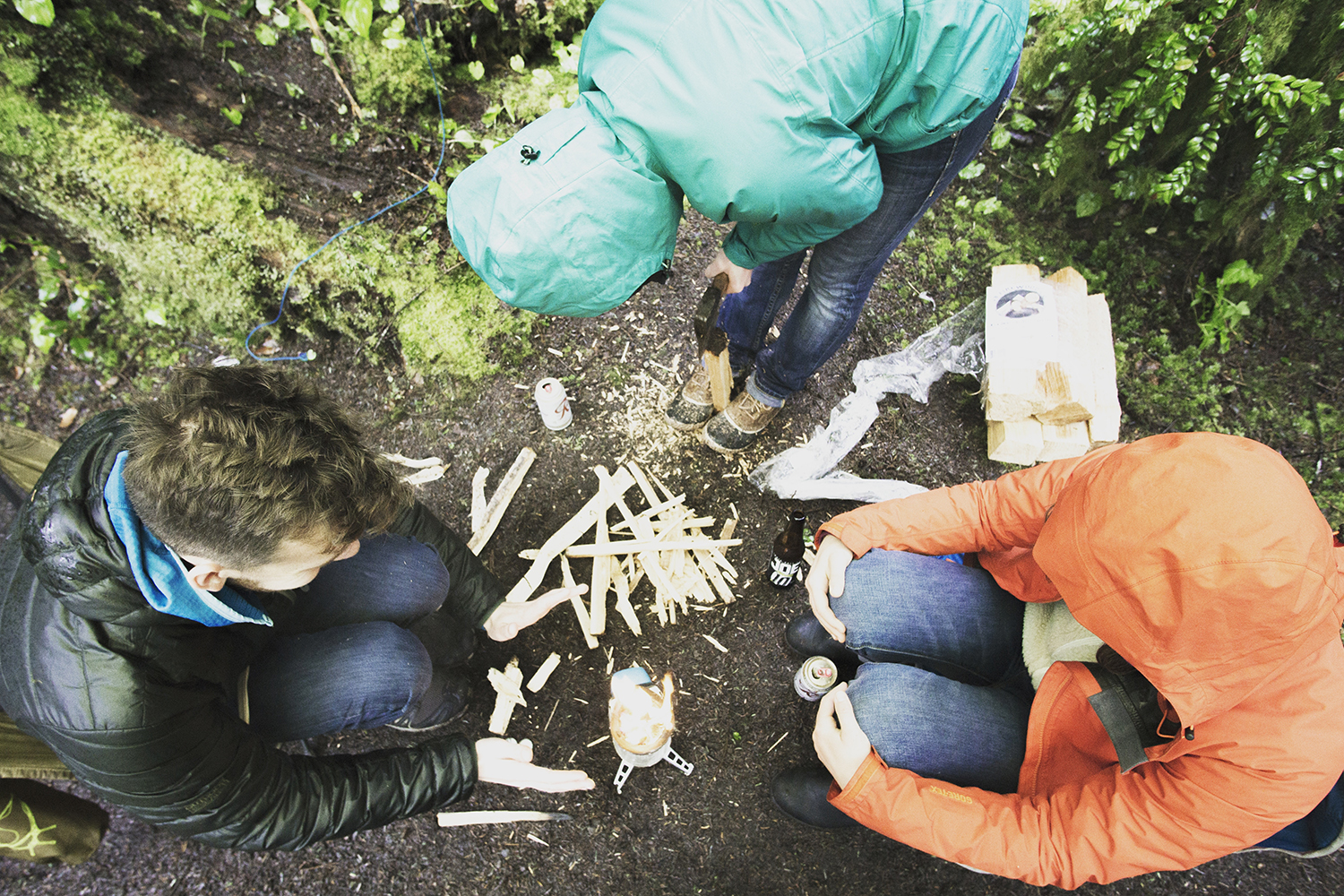 A group of people figuring out how to build a fire.