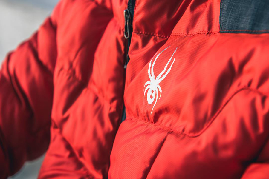 Closeup of white Spyder logo on a red ski jacket.