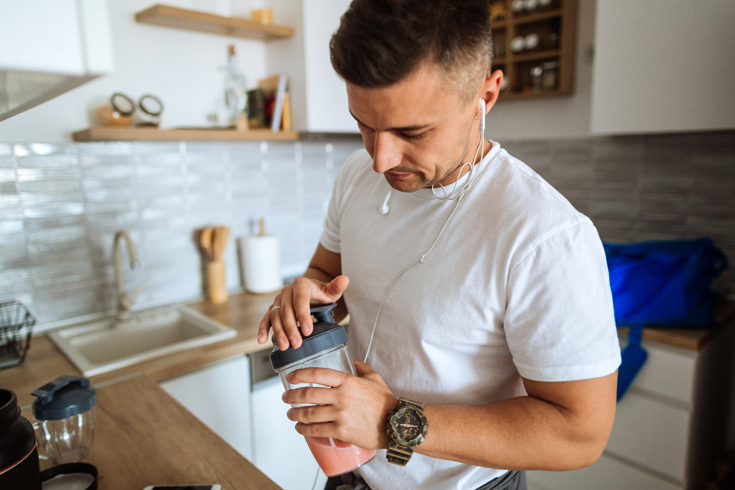 Man with a medium build preparing his protein shake in the kitchen.