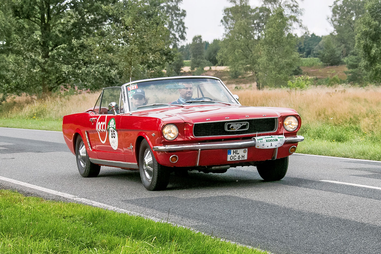 Red 1965 Ford Mustang Convertible being driven by a driver.