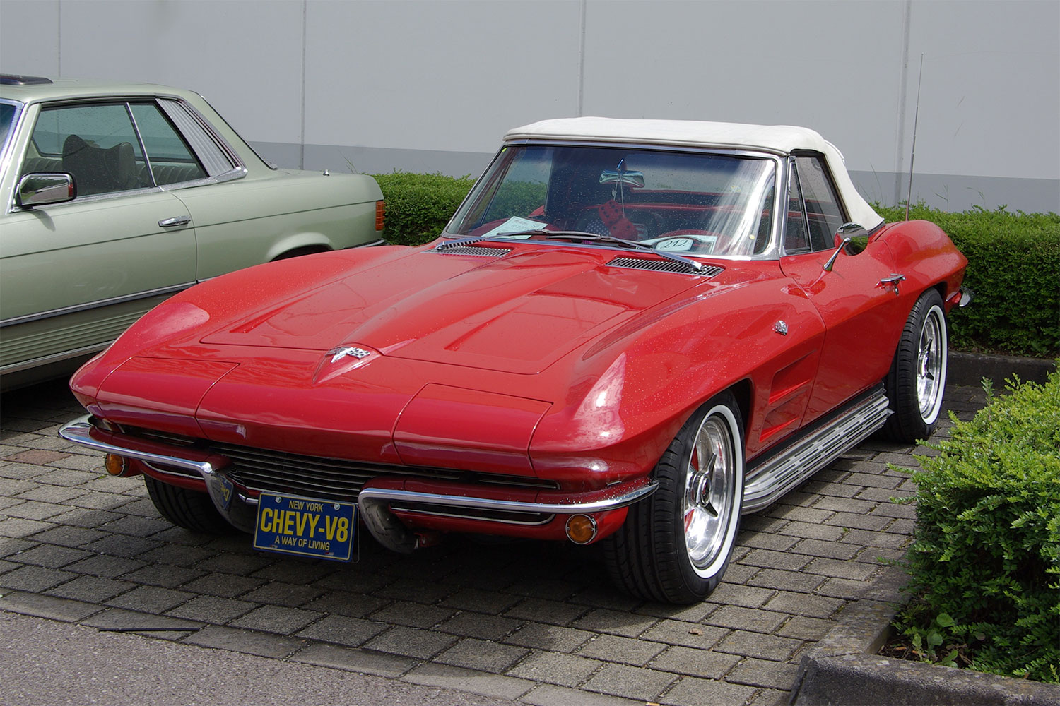 Red and White 1966 Chevy Corvette parked beside a silver one.