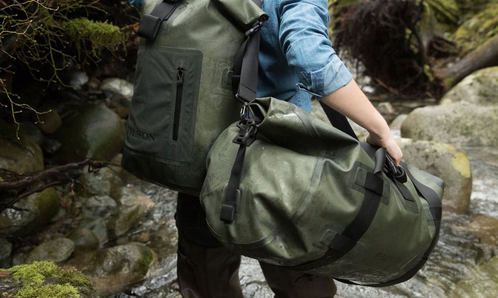 A hiker is seen from behind carrying two large bags.