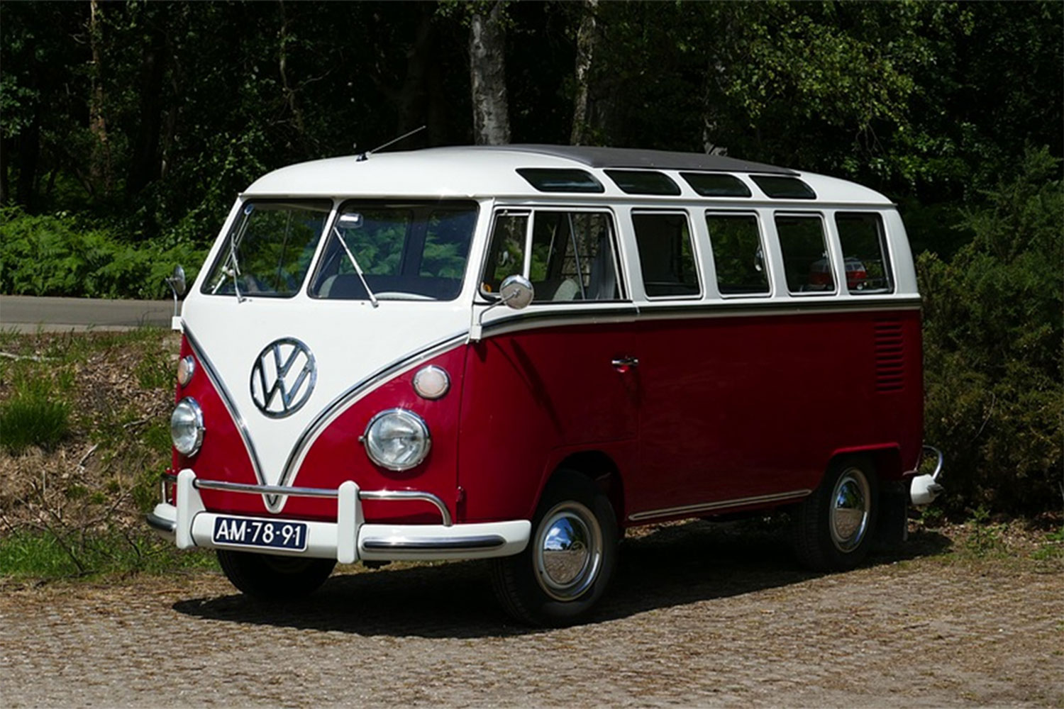 Red and White Classic Volkswagen Camper Van parked near the road.