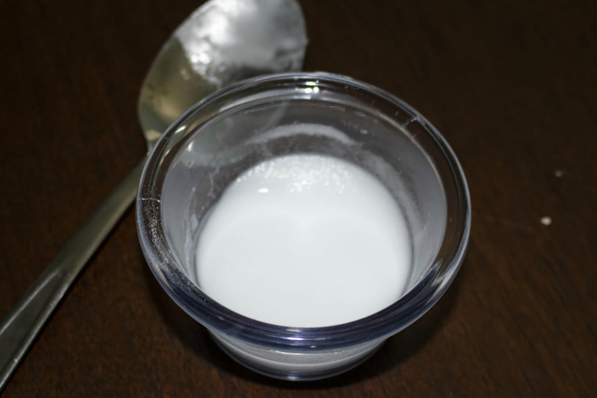 Baking soda paste on a small saucer with a tablespoon beside the saucer.