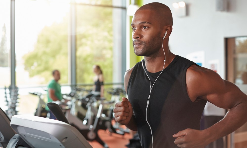 A man with earphones running on a treadmill.