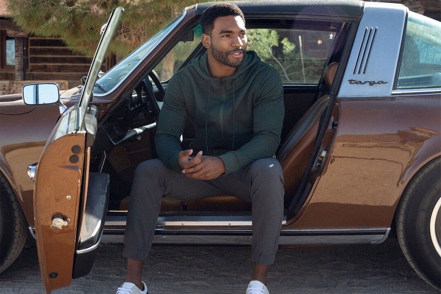 A man sitting on his car's driver seat.