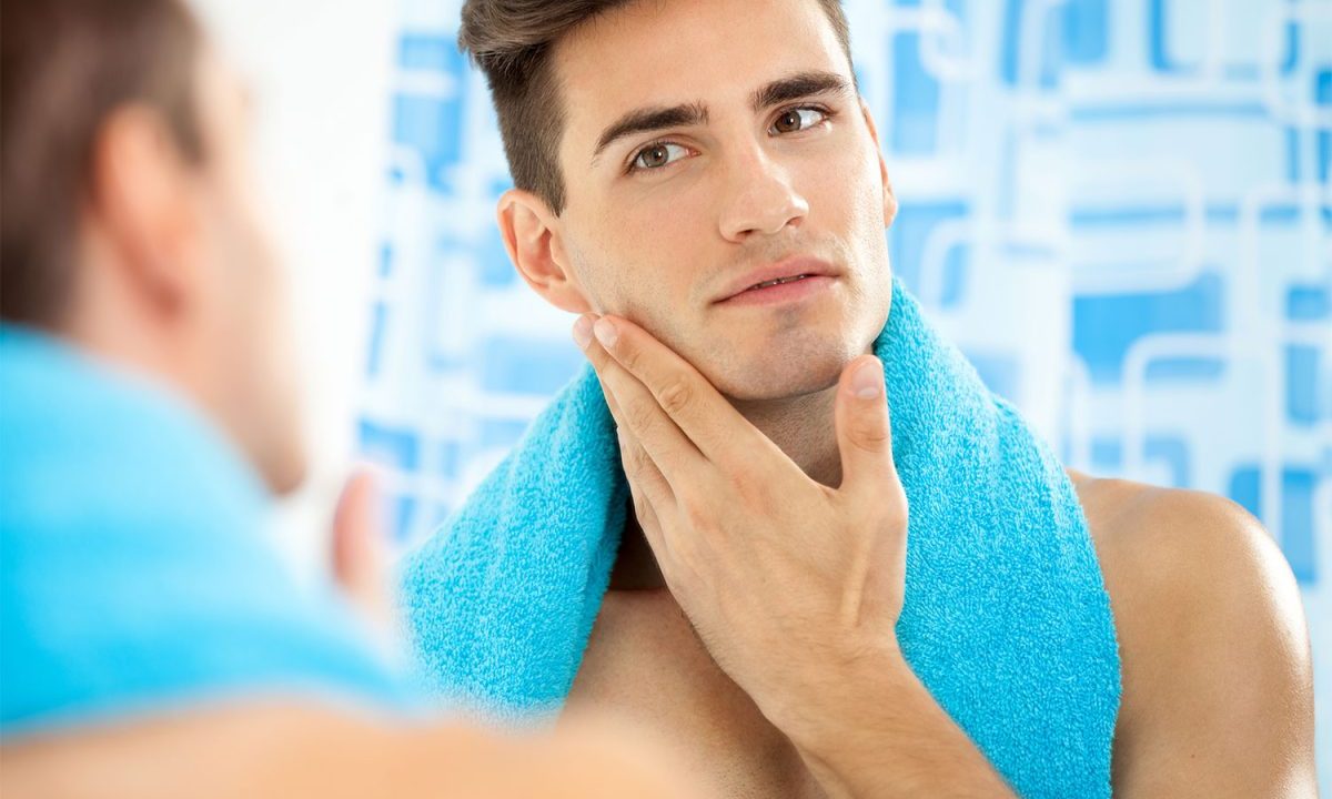 Man looking in the mirror with a blue towel around his neck