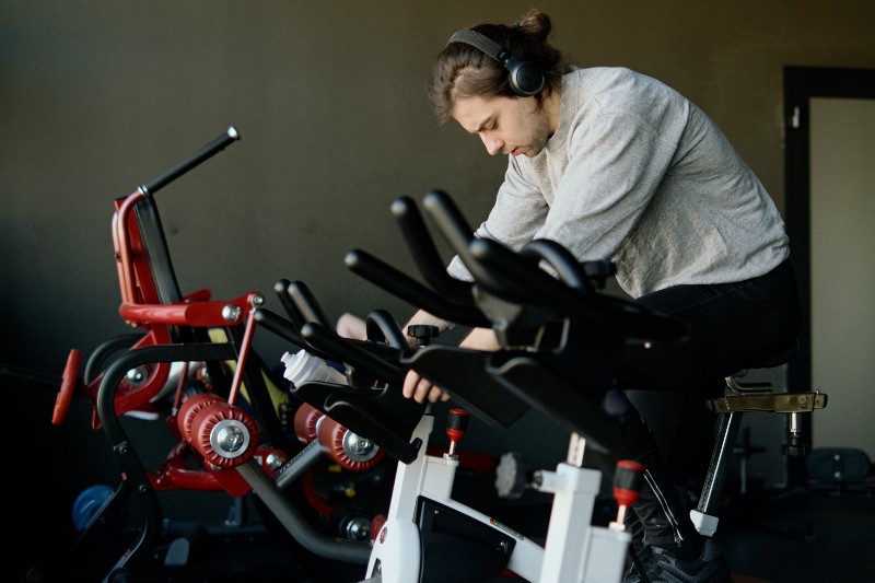 A man riding an exercise bike with headphones on.