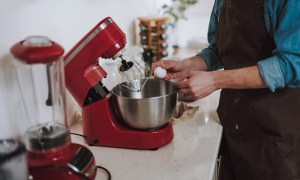 Person cracking egg on the bowl of electric stand mixer