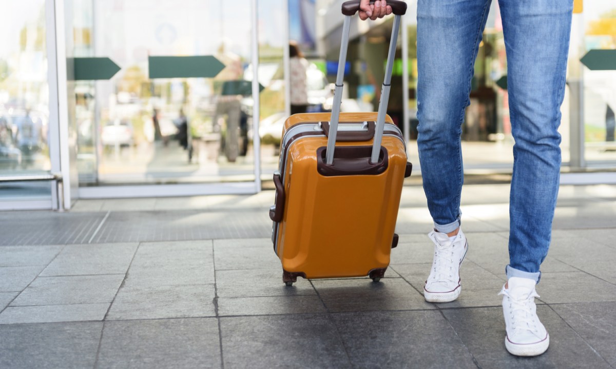 A person pulling a carry-on suitcase through the airport