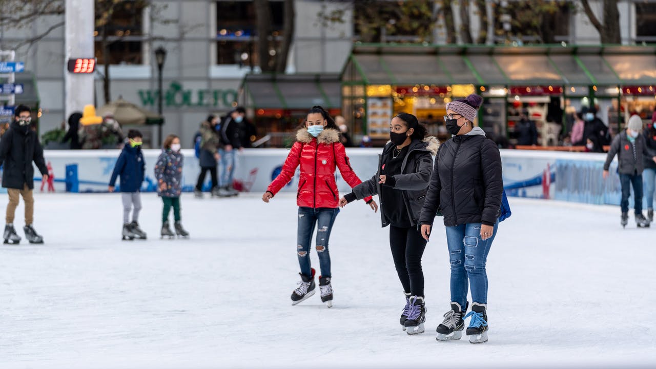 People bundled up and skating at an ice rink