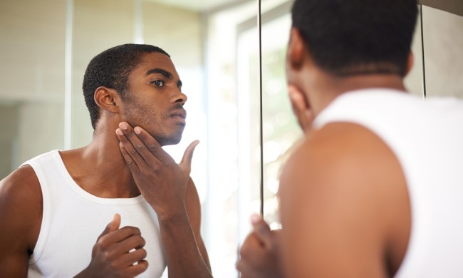 Guy looking at his skin in mirror.