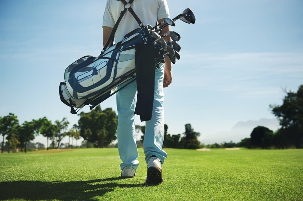 A golfer carrying their bag on the course.