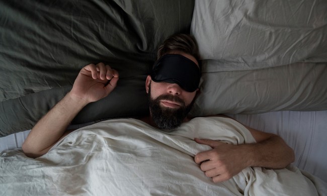 Man in a bed with a sleep mask.