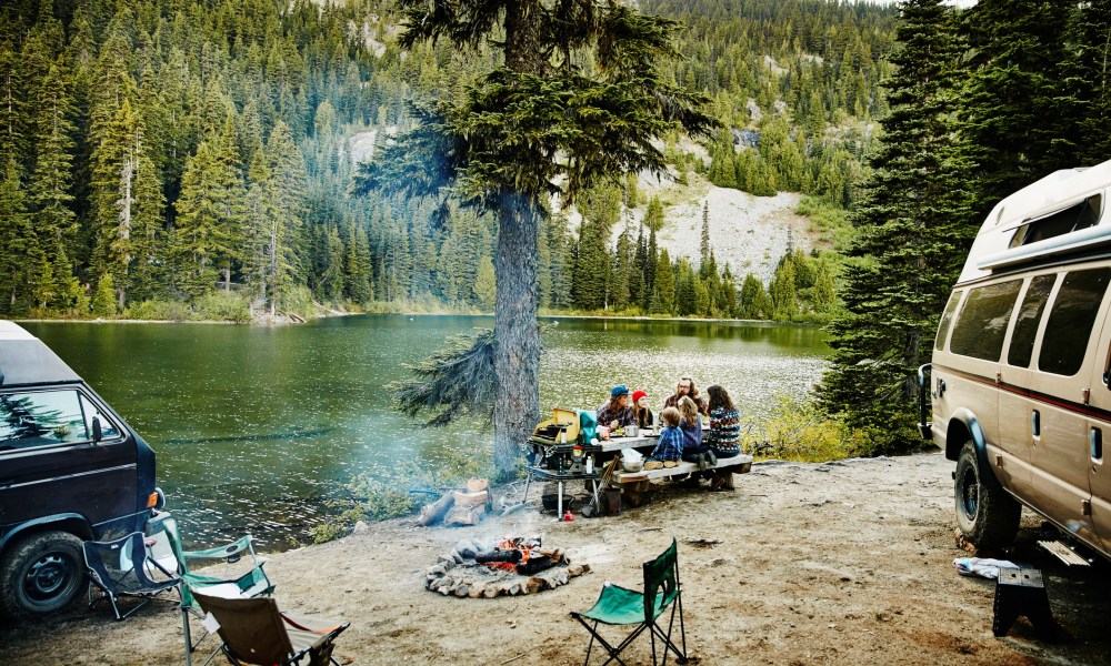 Friends sharing a meal while camping by a lake