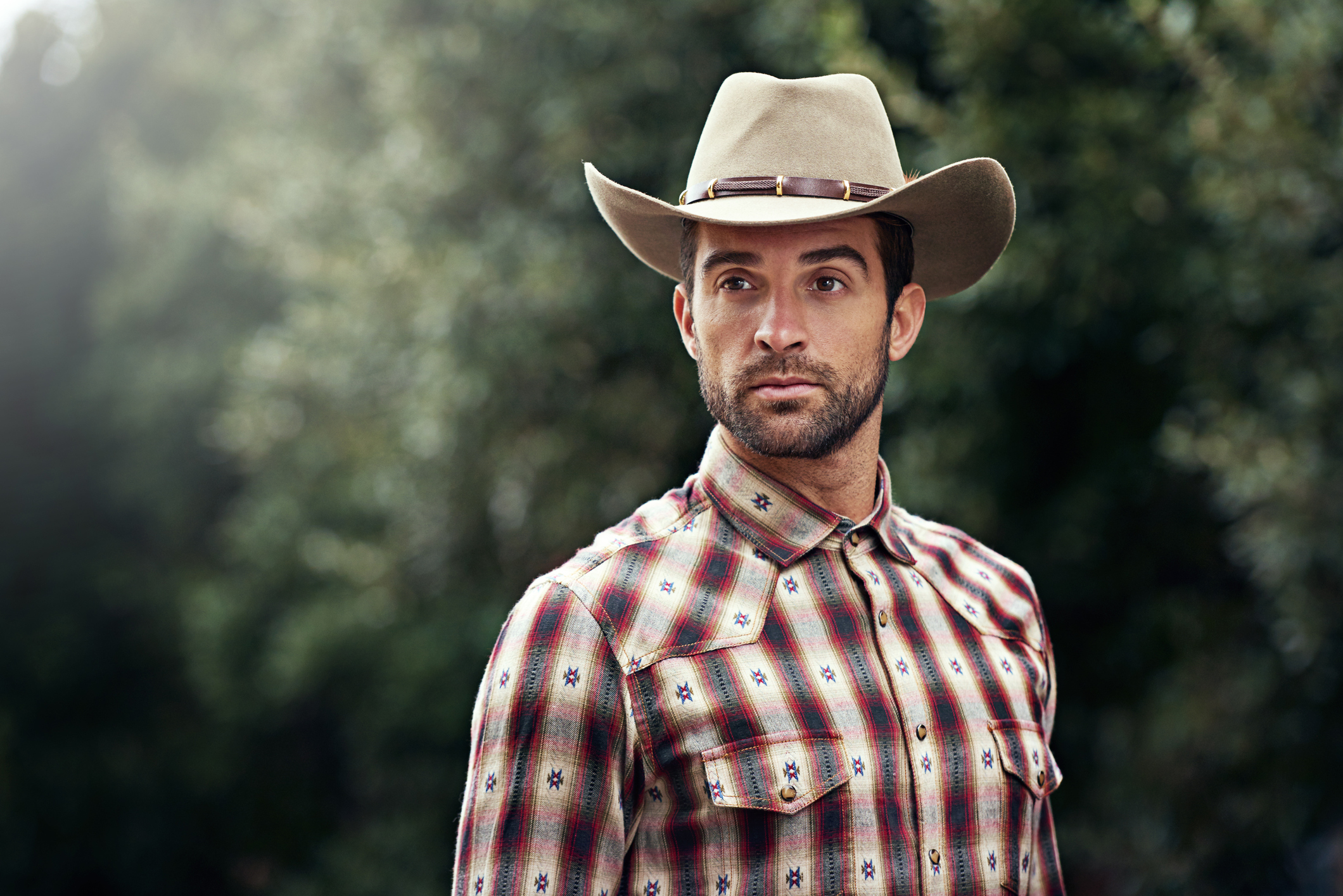 Shot of a handsome cowboy wearing a check shirt and stetson hat