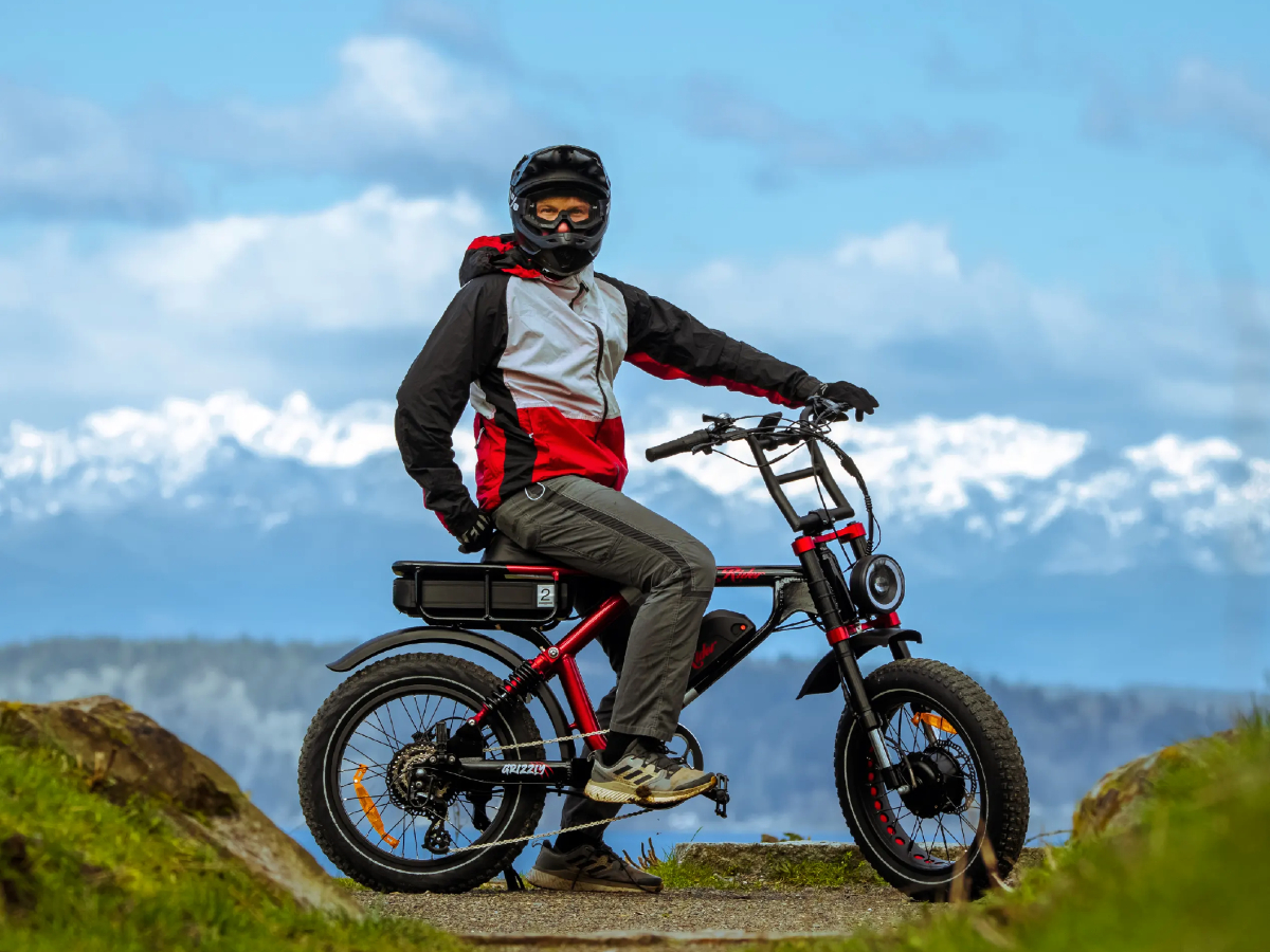 E-bike rider stopped on an Ariel Rider Grizzly with mountain views in the background.