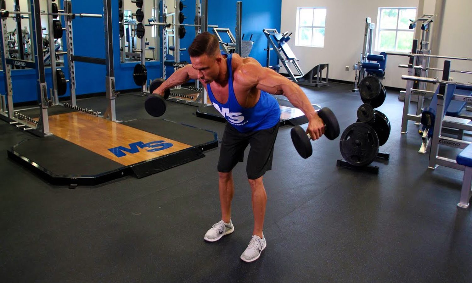 Man trying out a Bent-Over Reverse Fly with a dumbbell in each hand