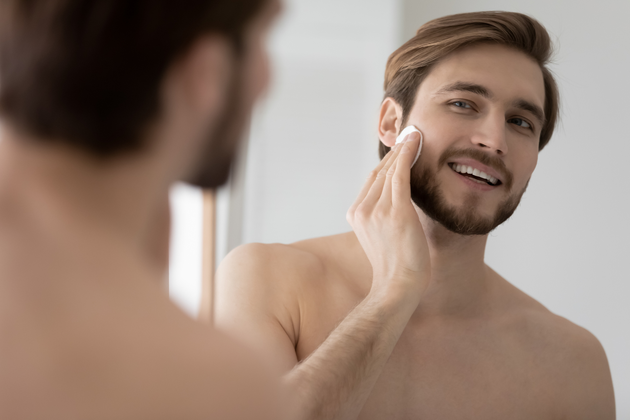 Man wiping his cheek with a cotton pad