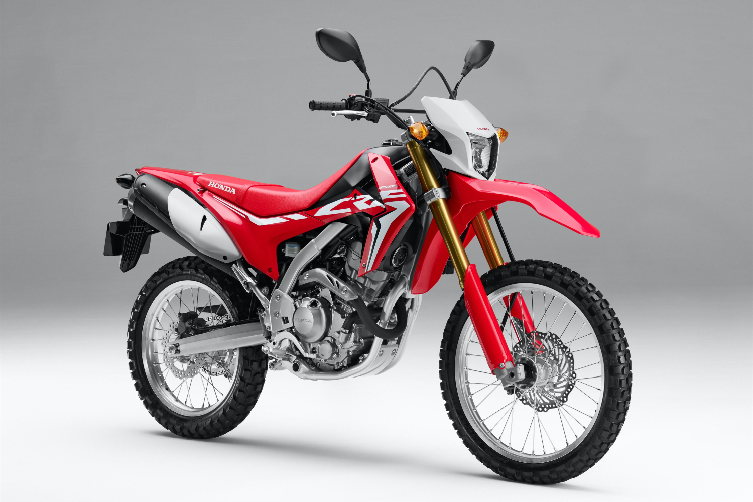 Front side profile of Honda CRF250L dirtbike motorcycle in a white backdrop. 