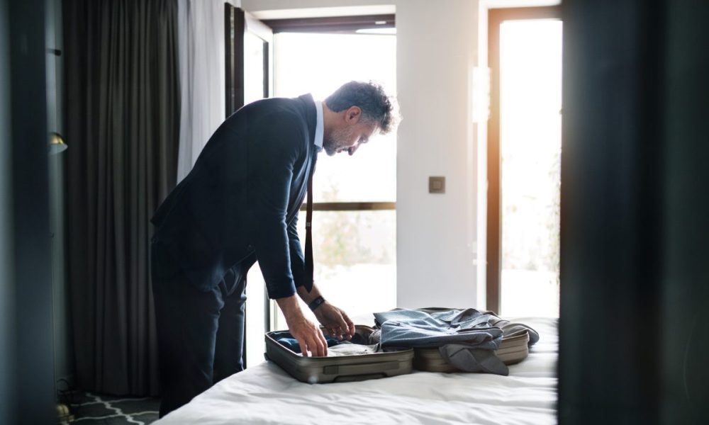 Person on a business trip packing up his suitcase.