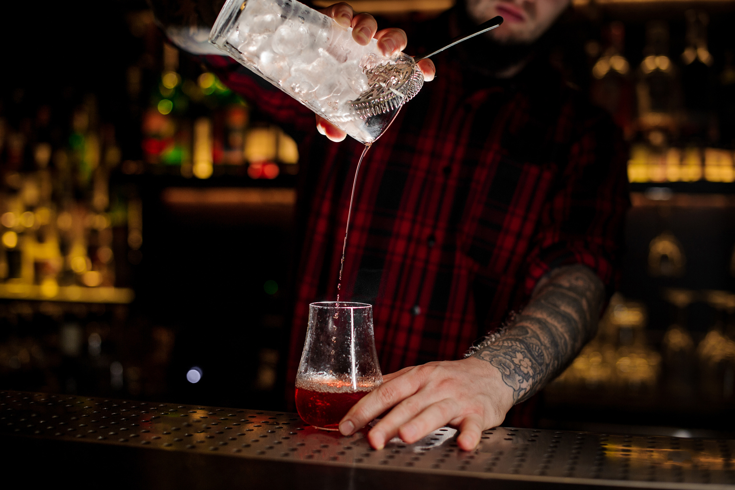 A bartender pouring a Sazerac cocktail.