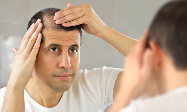 A man lookin at his thinning hair.