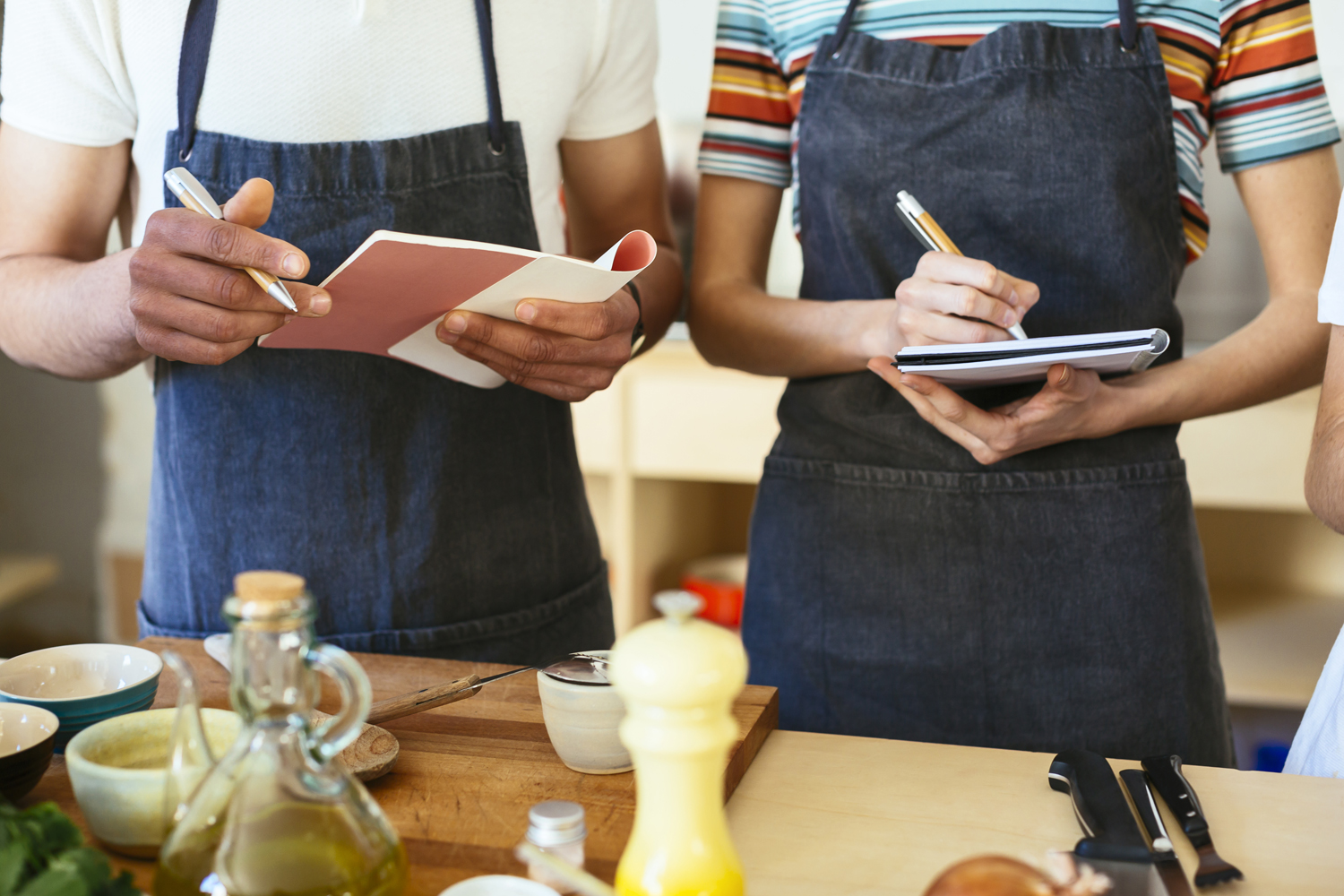 A close-up of a man and woman taking notes during a cooking class.