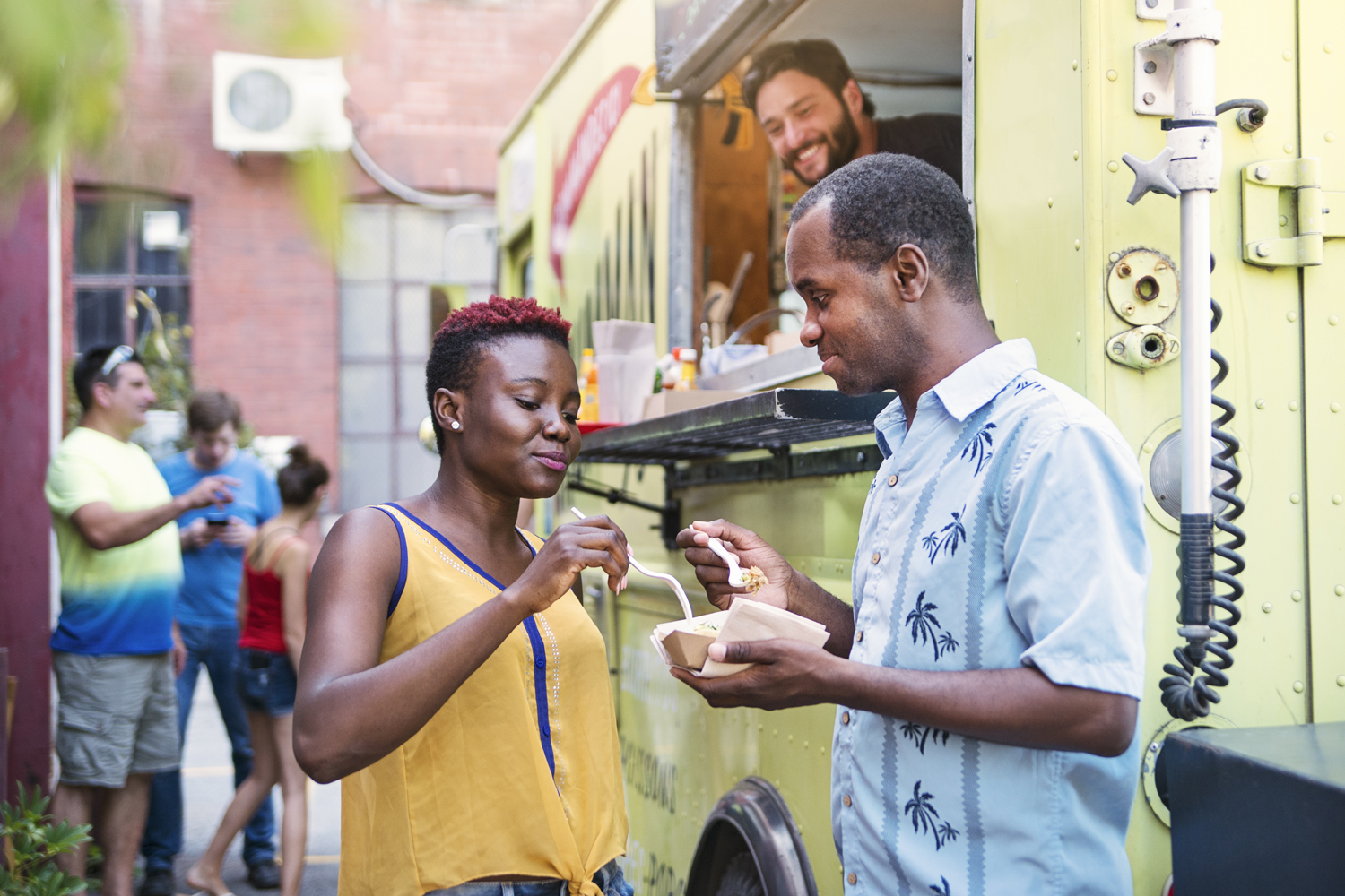 Couple eating lunch near a food truck.