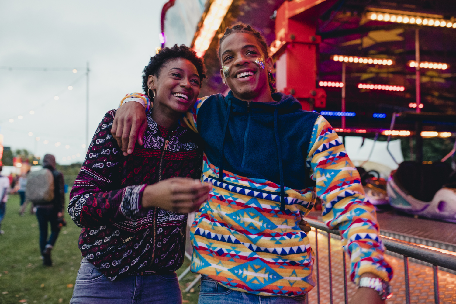 A smiling couple walking around the carnival.