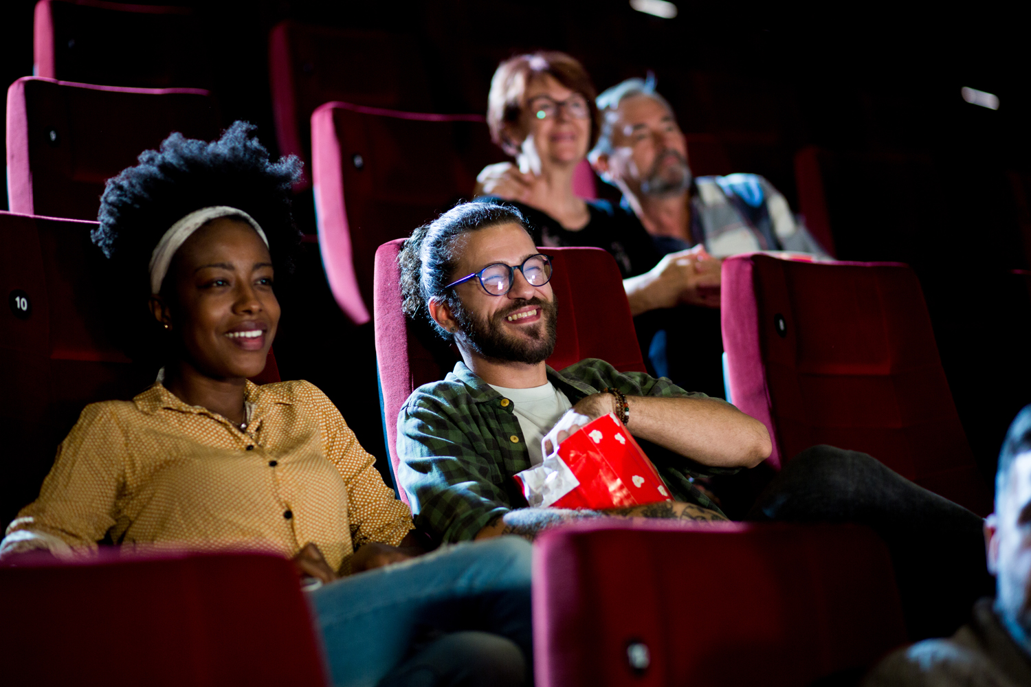 Young and old couples watching a movie in the cinema.