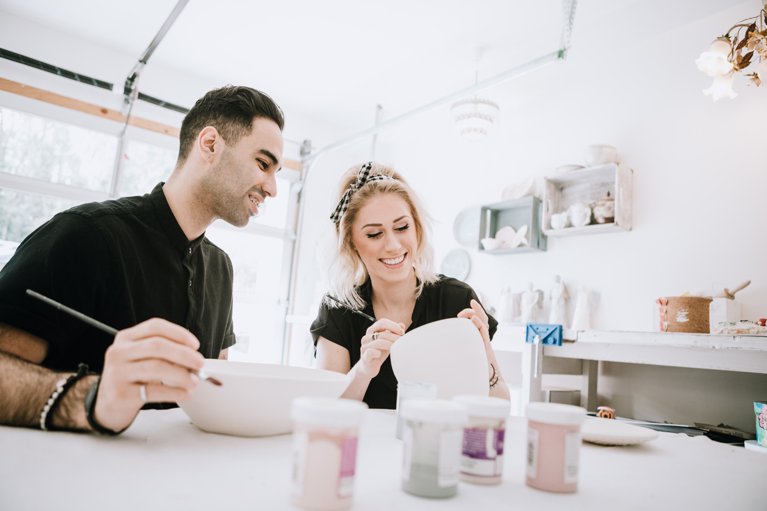 A couple painting their finished pottery pieces during art class.