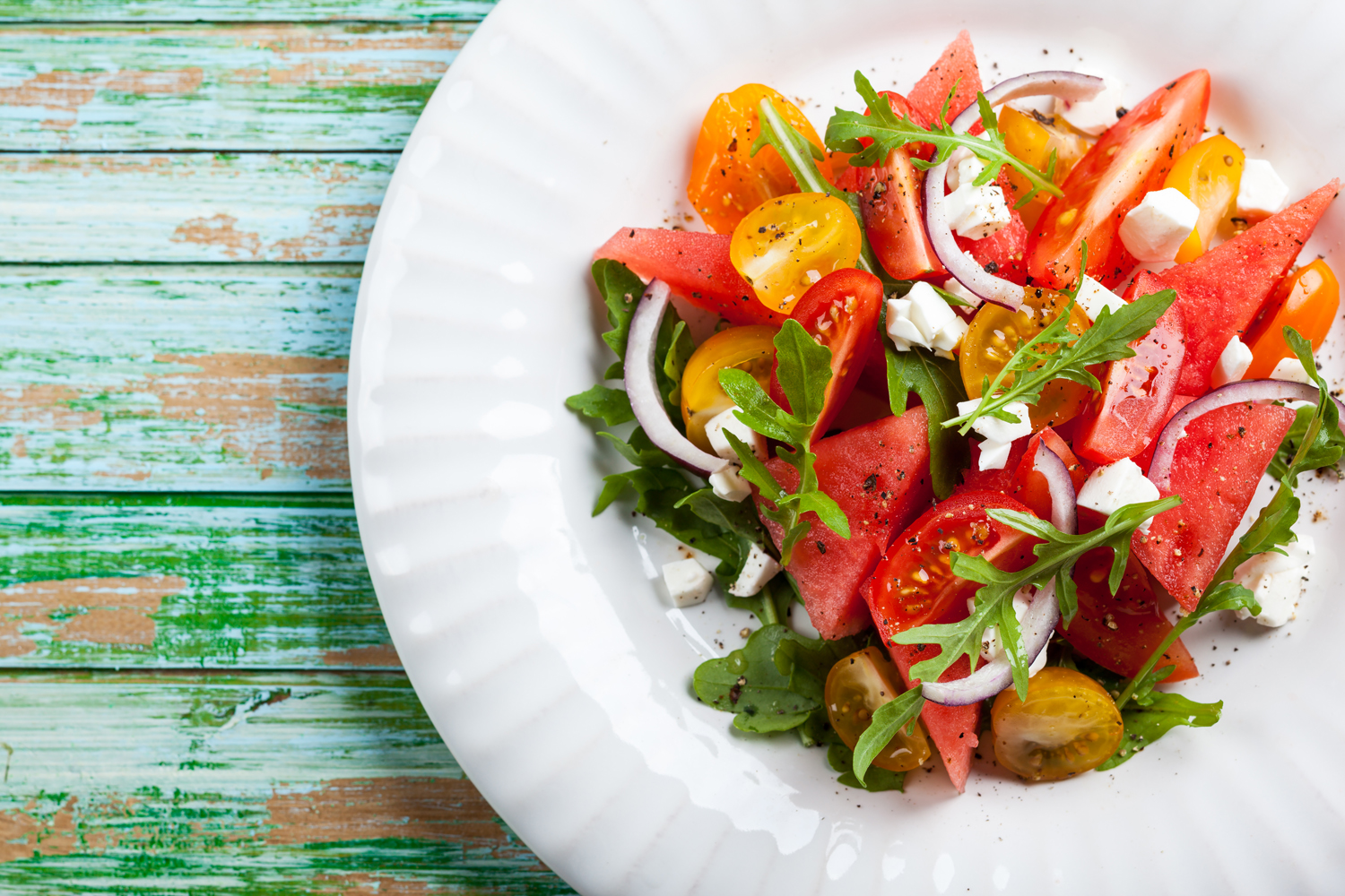 A plate of watermelon and tomato slices with Feta and balsamic sauce.