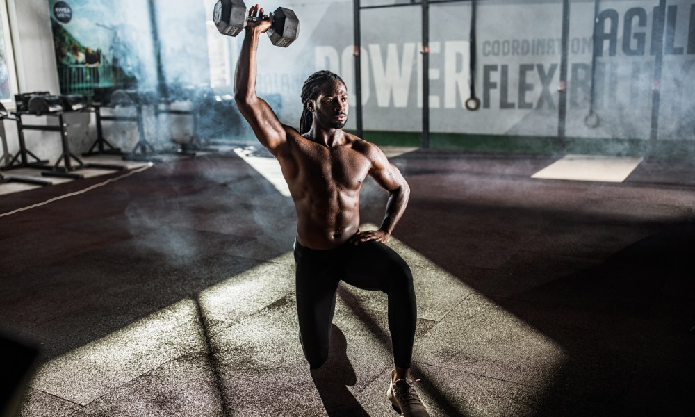 An athlete doing the single-arm reverse lunge and overhead press