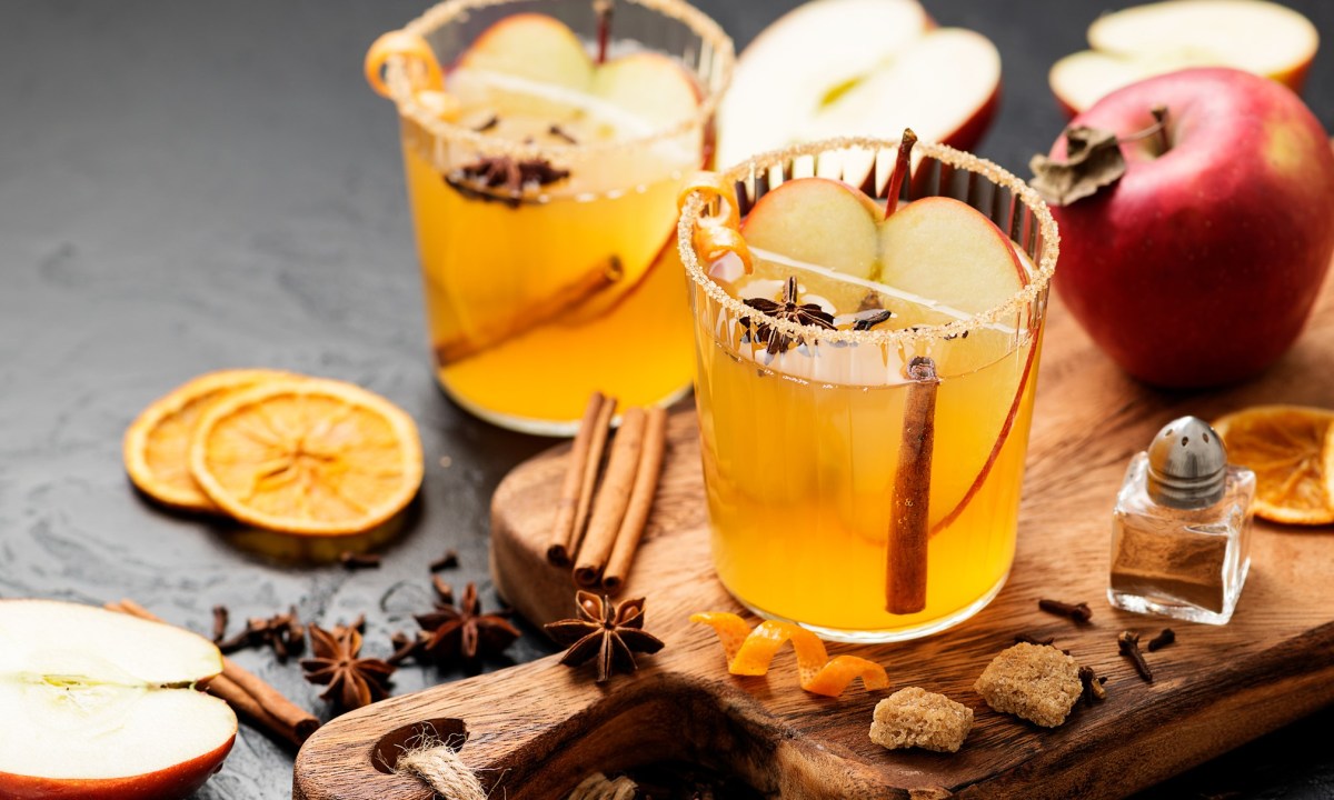 Hard apple cider spiced cocktail with sliced red apples, cinnamon, cardamom and star anise.