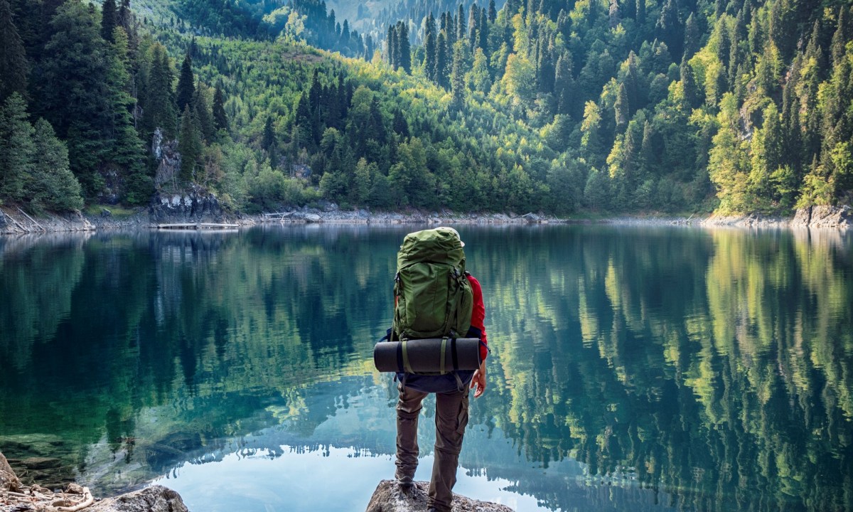 Hiker with a backpack in front of a mountain lake background