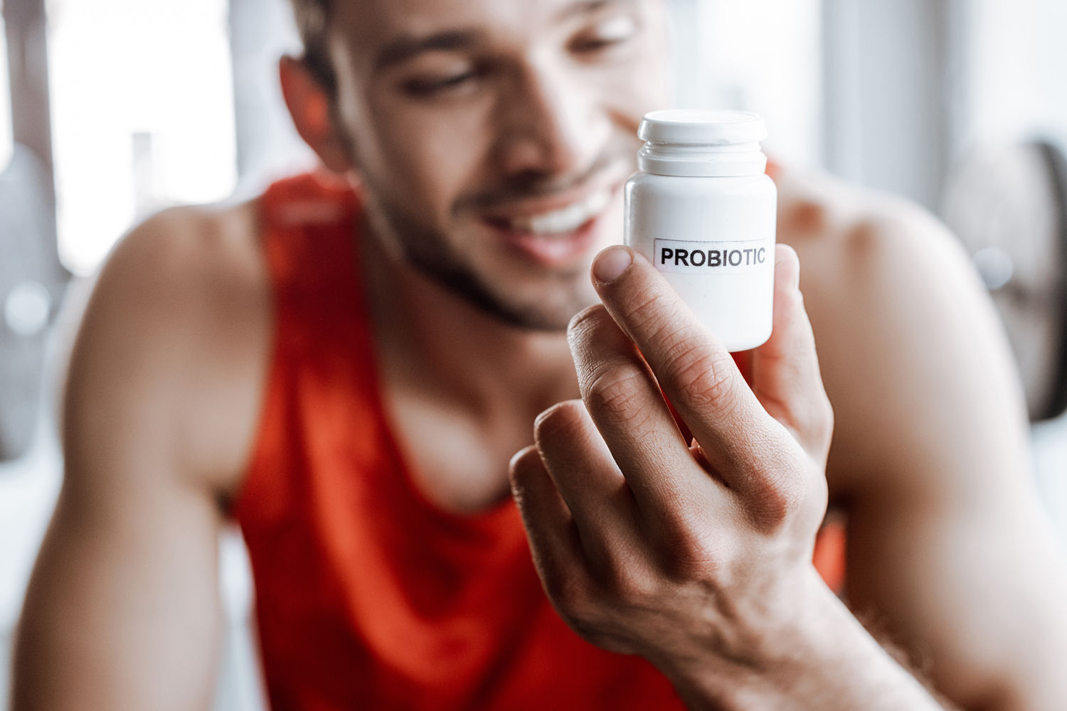 A smiling male athlete looking at a probiotic supplement.