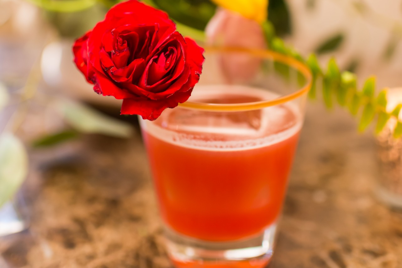 Roses & Pistols cocktail with flower garnish.