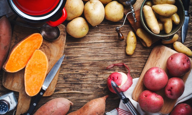 Variety of raw uncooked organic potatoes: red, white, sweet and fingers potatoes over wooden background.