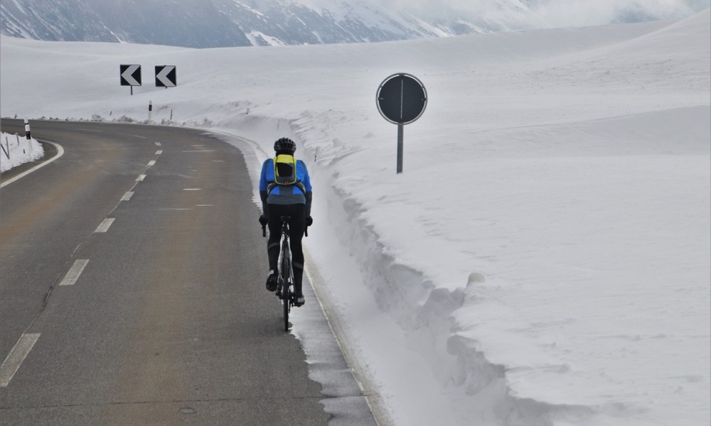 A man cycling in winter surrounded by snow.