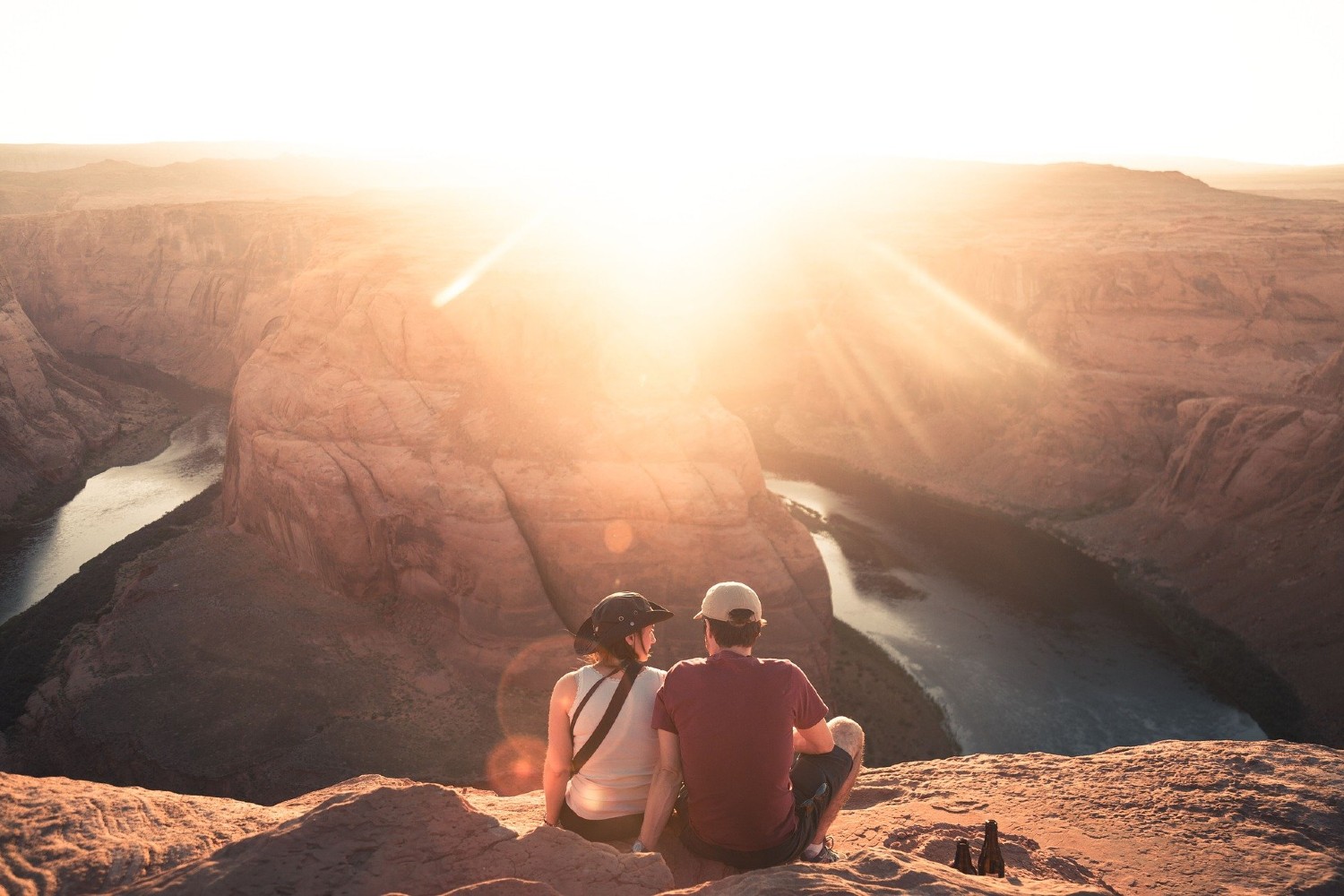 A hiking couple sit and watch the sunset over rocky outcrops