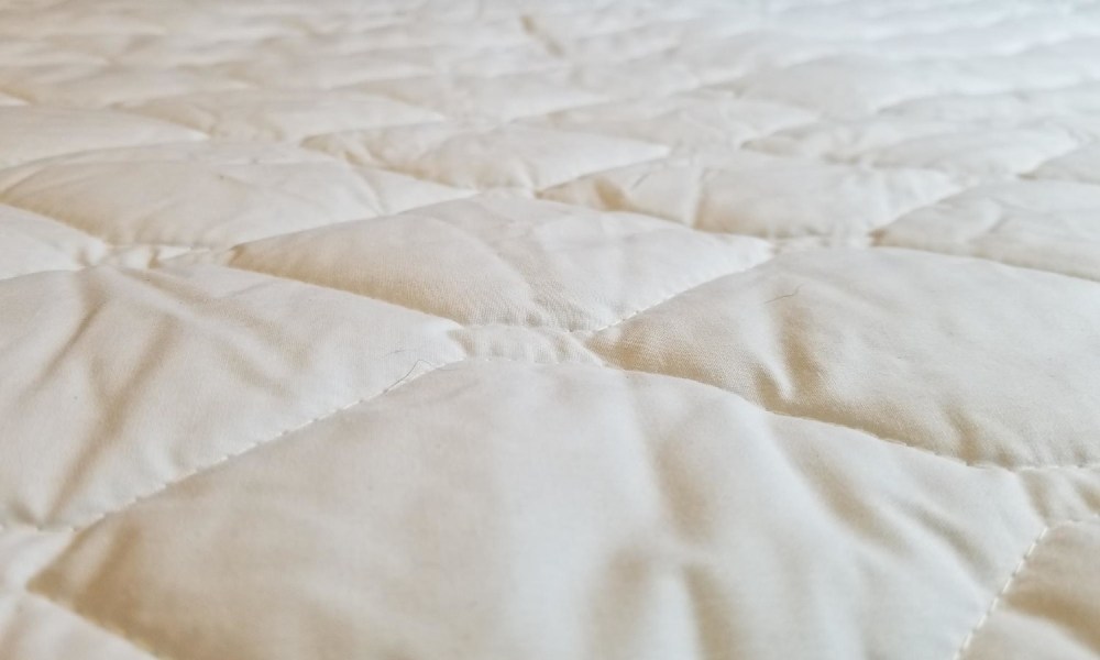 quilted mattress pad on a bed.