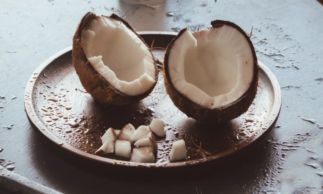 Cracked coconut served on a wooden plate.
