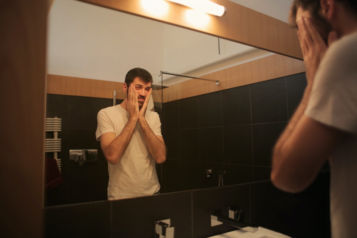 Man looking into mirror at his face,